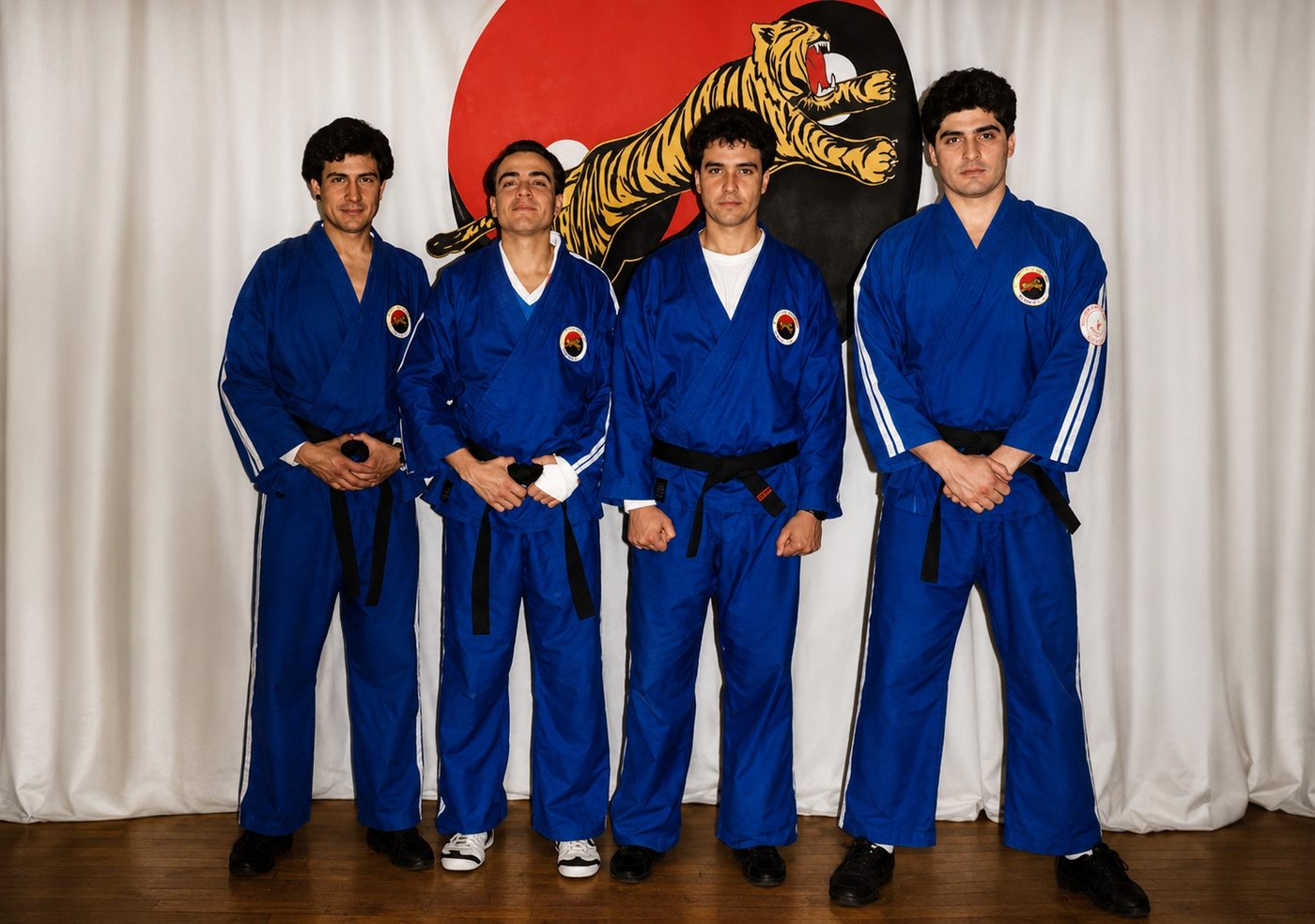Cuatro cinturones negros de la escuela frente al mural del tigre Shaolin Chan